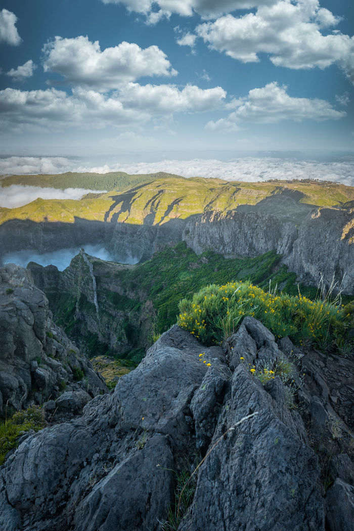 Scenic view of rocky cliffs and green vegetation under a blue sky with clouds in Madeira landscape.