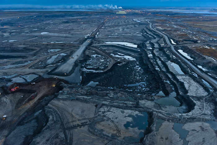 Aerial view of a muddy landscape with water pools and machinery, highlighting nature affected by wildlife photography themes.