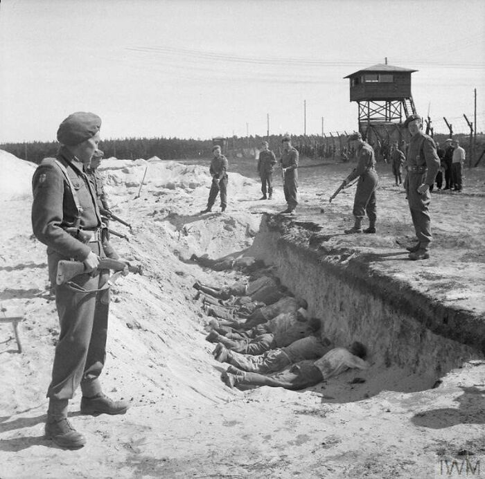 German SS Guards, Exhausted From Their Forced Labour Clearing The Bodies Of The Dead At Bergen-Belsen, Are Allowed A Brief Rest By British Soldiers But Are Forced To Take It By Lying Face Down In One Of The Empty Mass Graves, 1945