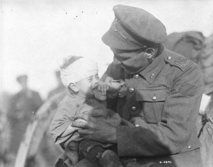 1ª Guerra Mundial. Soldado canadiense intentando consolar a un bebé belga herido, cuya madre ha muerto por un obús. Noviembre de 1918