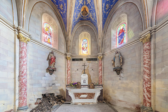 Interior of an abandoned church in Europe showing stained glass windows, religious statues, and damaged walls over eight years of travel.