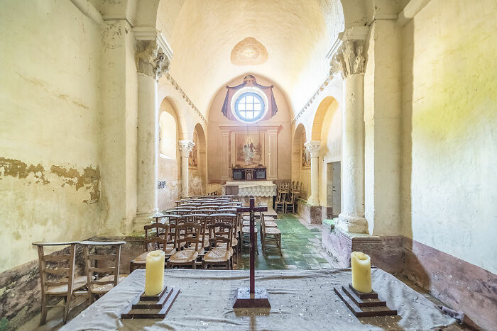 Abandoned church interior in Europe with old chairs, altar, candles, and peeling walls discovered during extensive travels.