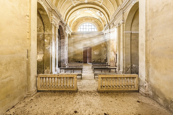 Interior of an abandoned church in Europe with sunlight streaming through windows, showcasing decay and forgotten history.