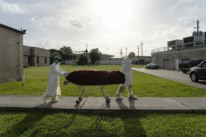 Personal médico con equipo de protección sacando una camilla con el cadáver de un paciente fallecido por Coronavirus, para llevarlo a un vehículo. 30 de Junio