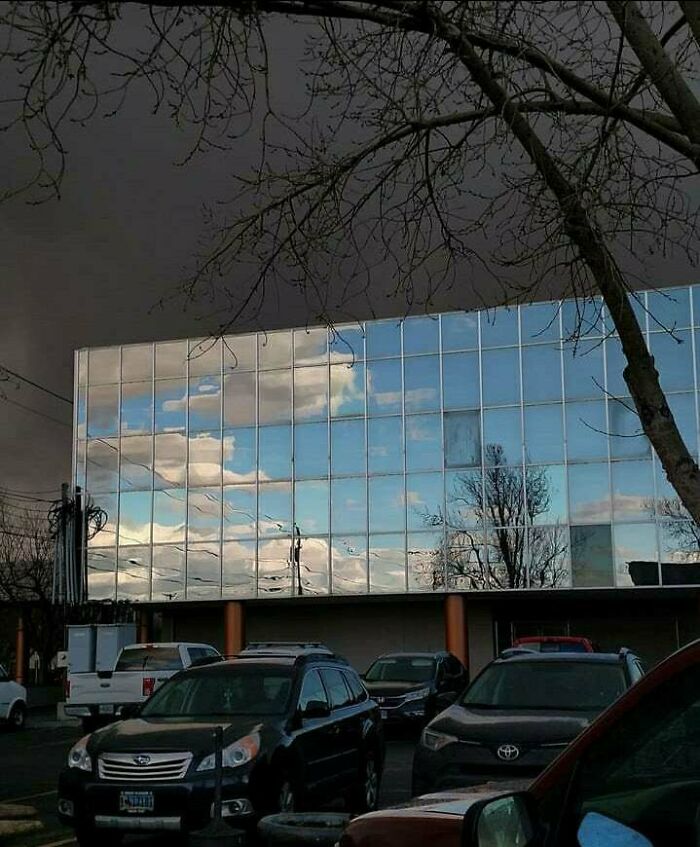 El cielo azul se refleja en el edificio vecino con la tormenta detrás de él