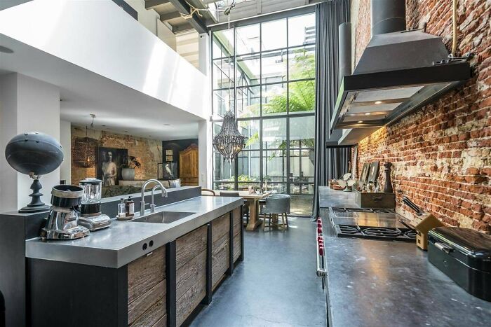 Kitchen Area Receives Lots Of Natural Light From The Two-Story Glass Wall In This Loft In Amsterdam