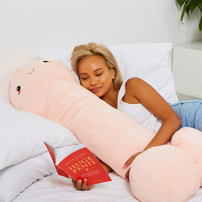 A Woman Hugging A Penis Body Pillow While Reading A Book Called "Huge Penis"