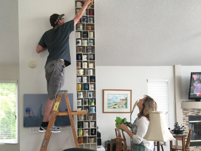 Couple arranging a tall mug shelf 