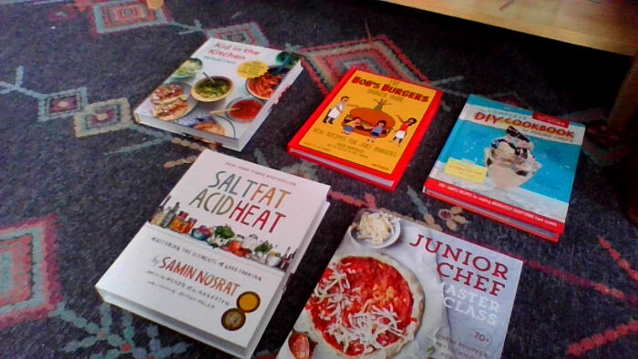 I Got Alot But My Favorites Are These Cookbooks (Top Left: Kid In The Kitchen. Top Middle: The Bob's Burgers Burger Book. Top Right: The Complete DIY Cookbook. Bottom Left: Salt Fat Acid Heat. Bottom Right: Juinor Chef Master Class.)