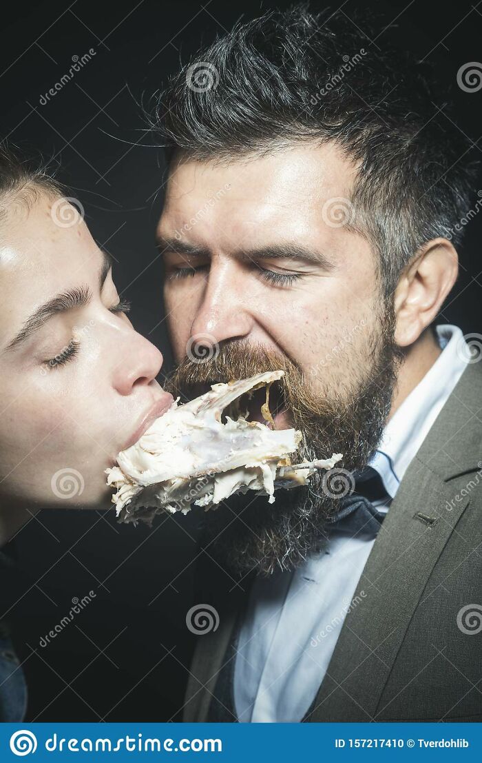 Couple Enjoys Meal, Meat Or Fowl. Man And Woman With Chickens Skeleton In Mouths On Black Background. Couple Eats Chicken Together. Enjoy Your Meal Concept. Weird Aesthetics, Closeness And Intimacy.