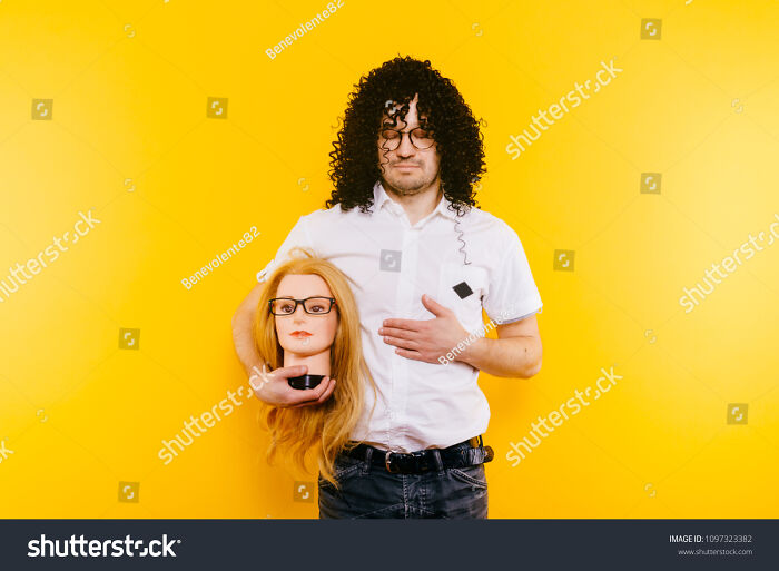Excited Bizarre Strange Odd Foolish Guy Have Fun With Plastic Mannequin. Weird Relationship. Happy Adult Man In Black Curly Wig Isolated On Yellow Background. Oddball Rebel With Hairy Girl Head