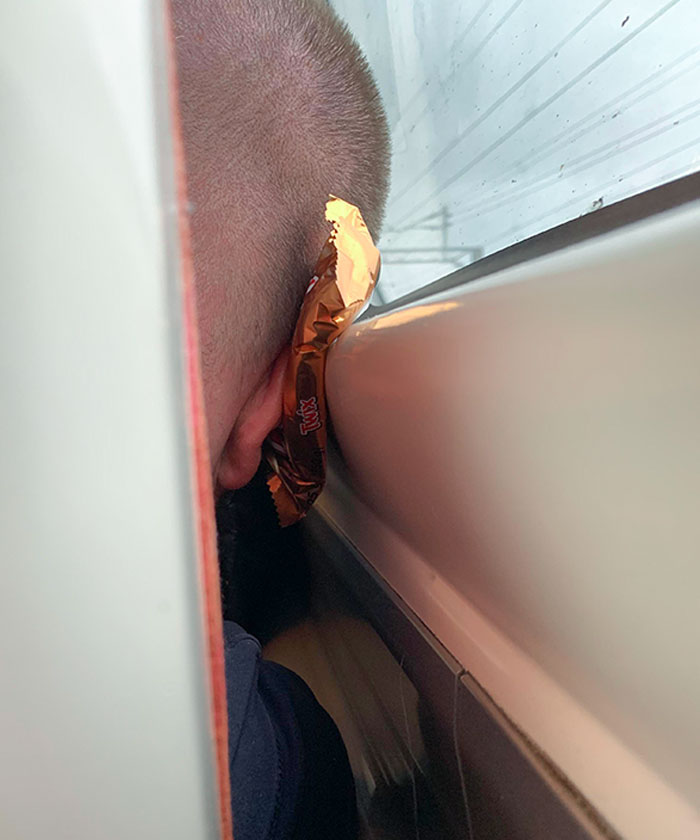 El hombre que está sentado delante de mí en el tren está usando un Twix como almohada