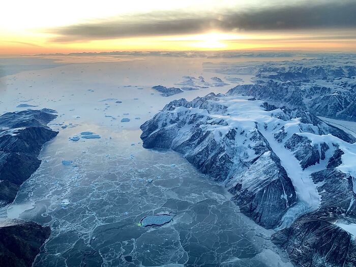 Aerial view of a dramatic, icy landscape with snow-capped mountains and a frozen sea, an unbelievable photo on Earth.