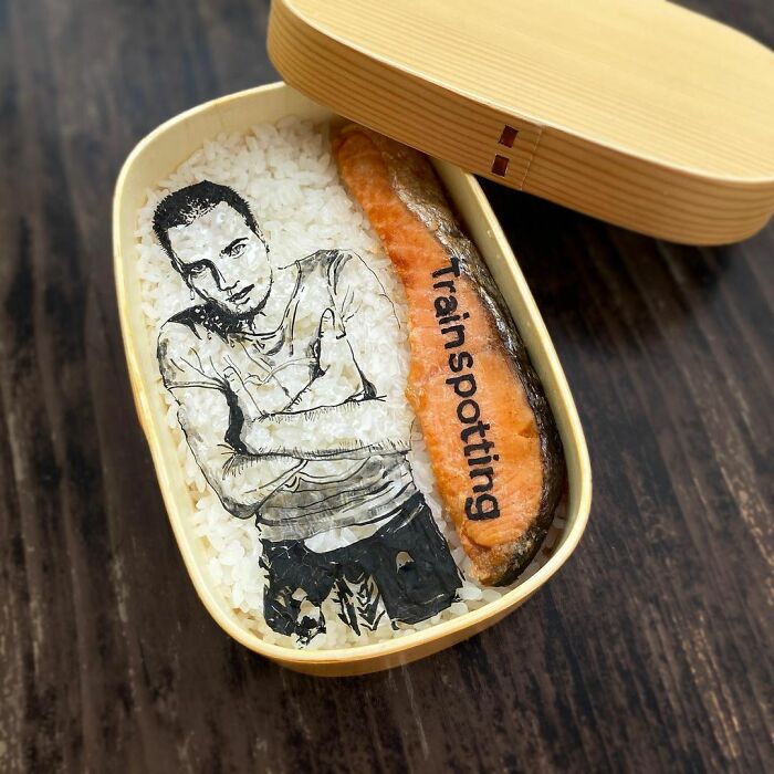Bento artist lunchbox featuring detailed edible art of Trainspotting character on rice with salmon fillet.