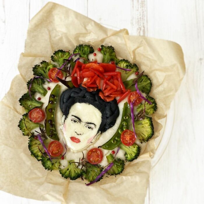 Bento artist creates detailed lunchbox art featuring a popular portrait surrounded by fresh vegetables and colorful garnishes.