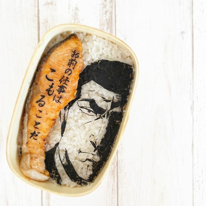 Bento artist creates detailed lunchbox featuring anime character face made from rice and seaweed with salmon slice.