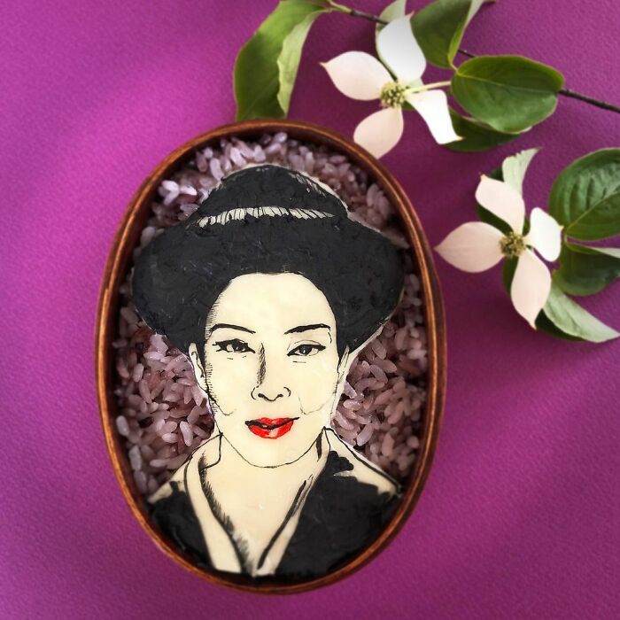 Bento artist creates detailed lunchbox with rice and edible portrait of a woman wearing a hat inspired by TV shows and manga.