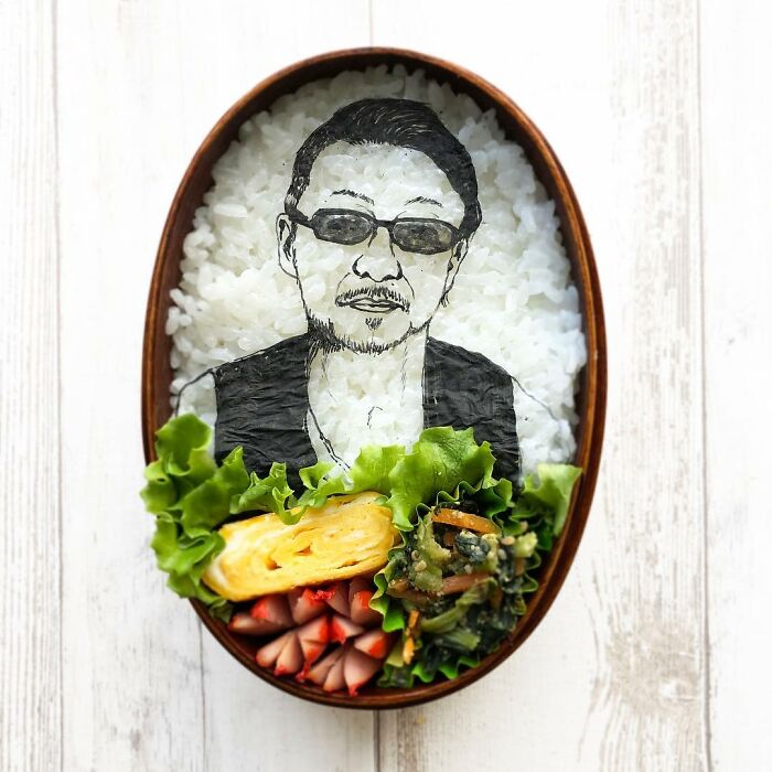 Bento artist creates detailed lunchbox portrait of a man using rice, seaweed, and assorted vegetables.