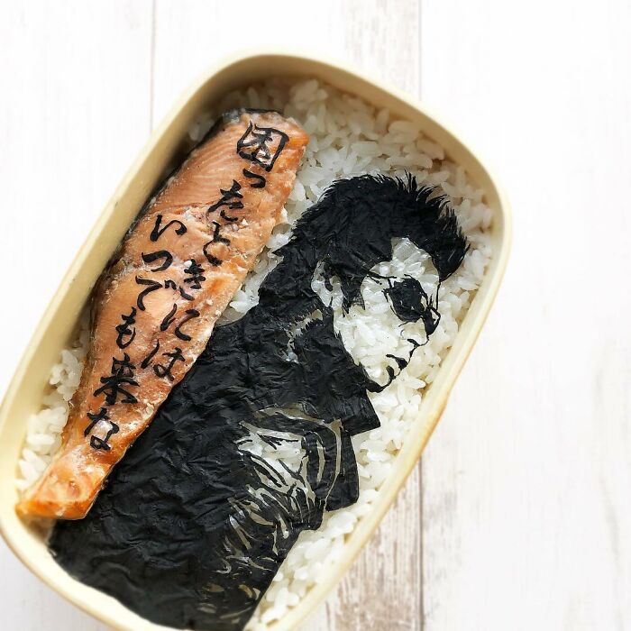 Bento artist creates detailed lunchbox featuring a character from TV shows and manga using rice, seaweed, and salmon.