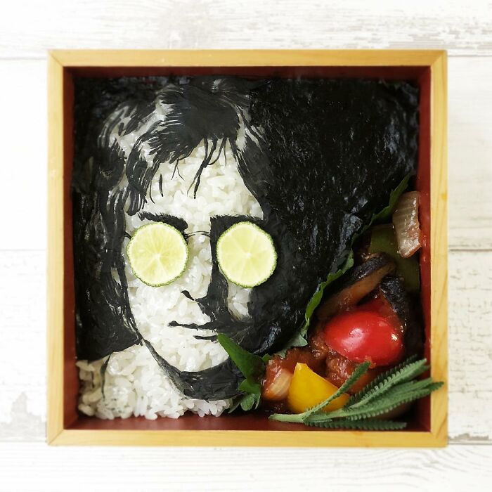 Bento artist lunchbox featuring portrait of a man with lime glasses made from rice and seaweed with vegetables.
