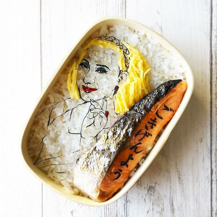 Bento artist creates detailed lunchbox art featuring a character portrait with rice, egg, and grilled fish.