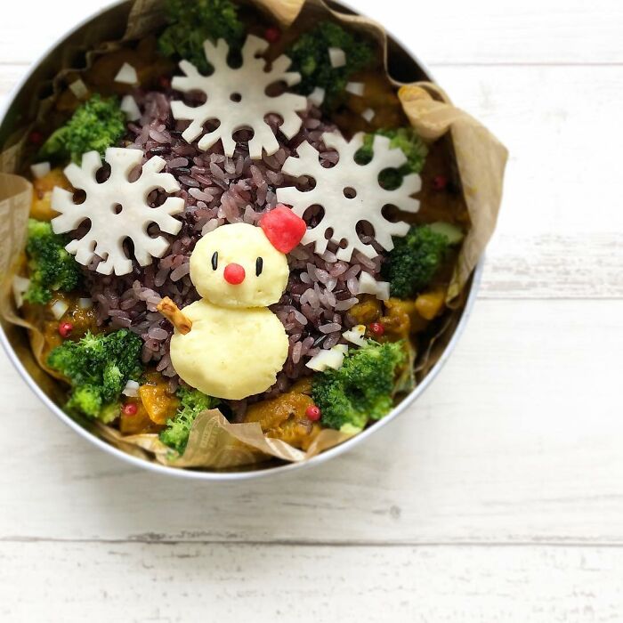 Bento artist’s creative lunchbox featuring a snowman made of mashed potatoes and snowflake-shaped cheese on rice.