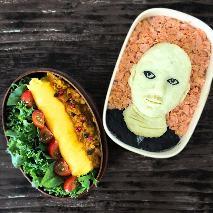 Bento artist lunchbox featuring detailed edible portrait with fresh vegetables and vibrant ingredients on wooden surface
