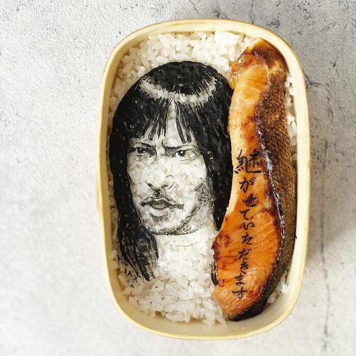Bento artist creates detailed lunchbox with rice portrait and grilled salmon inspired by favorite TV shows and manga.
