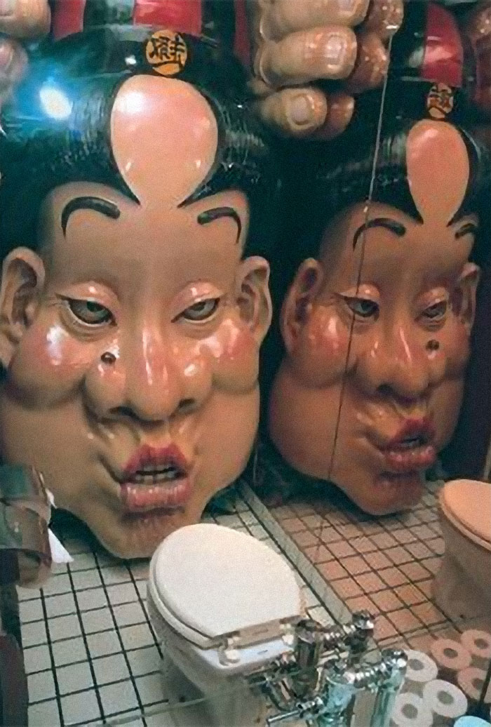 Situado en un bar en Shinjuku, Japón. Hay un cuarto de baño con una cabeza pintada situada delante del retrete. Activada por la presión del asiento, la cara canta una extraña melodía de borrachera y se mueve lentamente hacia ti... haciendo la habitación cada vez más pequeña, hasta que sus labios te "besan" las rodillas.