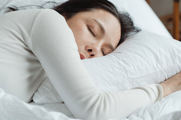 woman in white long sleeve shirt sleeping on bed