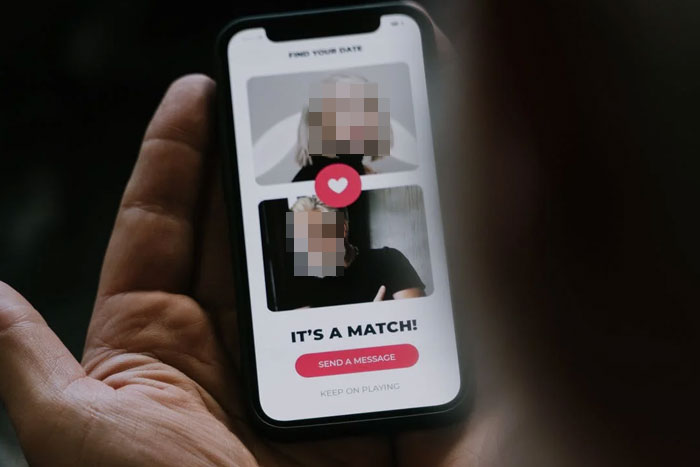 person holding a phone with a dating app open