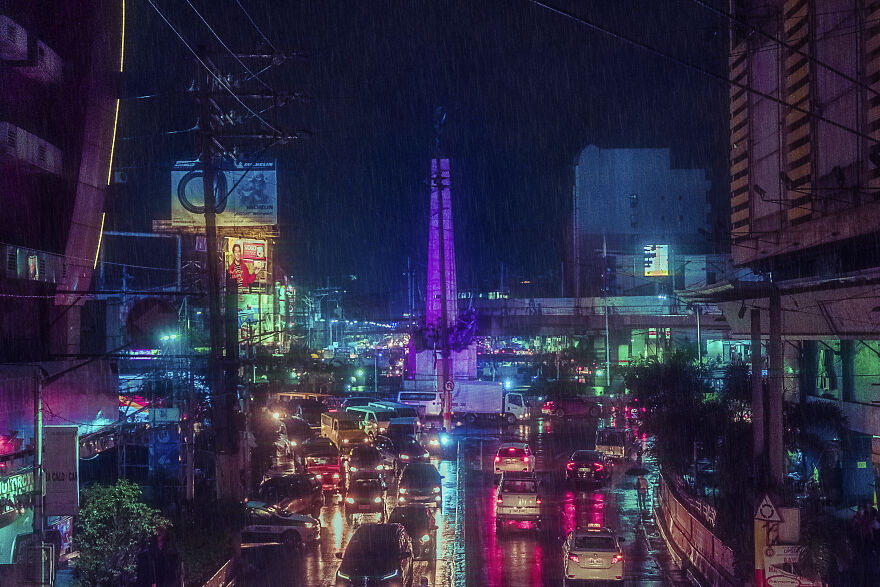Monumento Circle During A Rainy Monsoon Night. A Historical Monument Surrounded By Motels, Billboards, Shopping Malls, And A Nightlife District