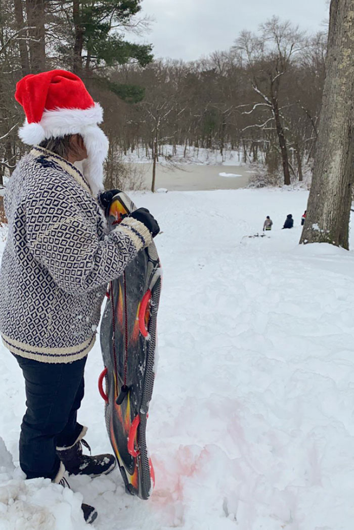 Neighborhood Kids Were Using This Lady’s Yard For Sledding Without Asking. She Responded By Blasting Xmas Music Out Her Window, Putting On A Santa Hat With A Beard And Joining Them