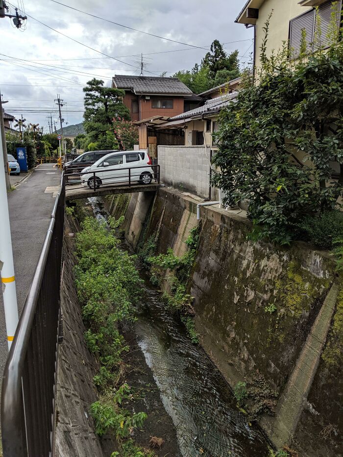 El coche está estacionado en el camino de entrada que está construido sobre un pequeño arroyo en Kioto, Japón