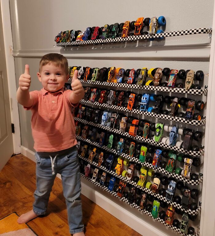 Hice un estante de pared para almacenar/mostrar los Monster Trucks de mi hijo. Por menos de 20 dólares, usé barras de cortina y cinta adhesiva de banderas a cuadros