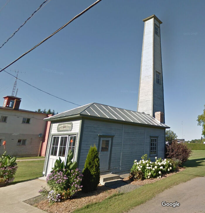 What Is This Giant Tower? It Has Windows On The Side, And It Can't Be Much Wider Than A Staircase. It Is Connected To A Tiny House Labeled ''fire Station''. Small Town In Quebec, Canada