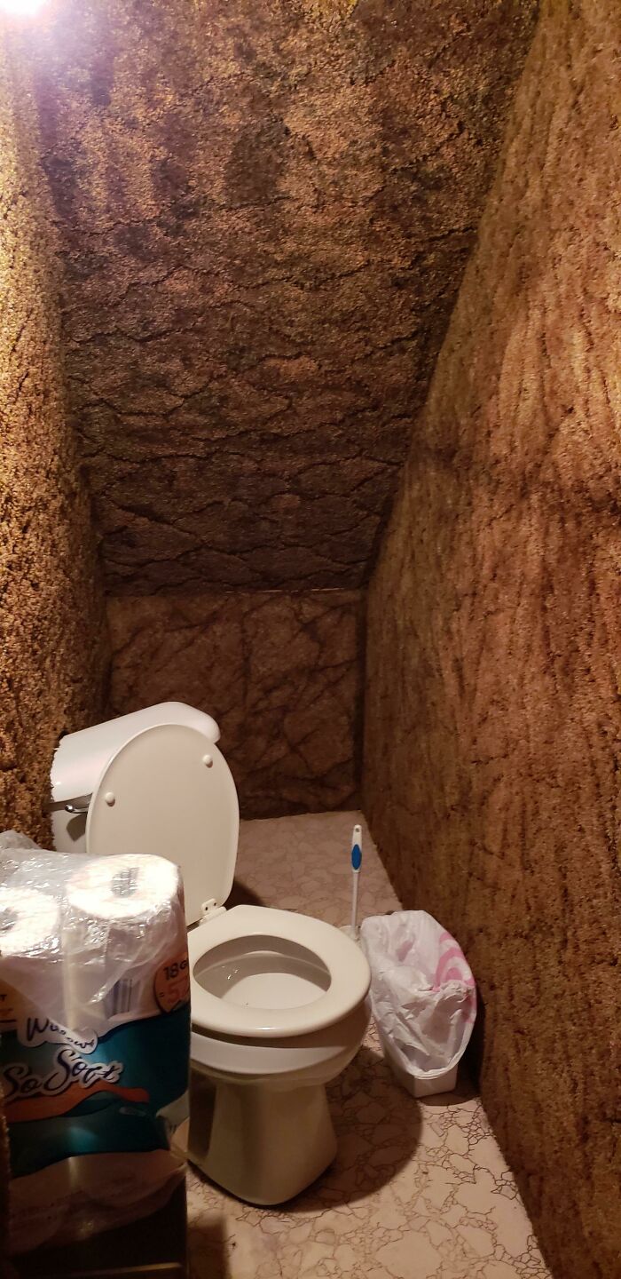El "baño" bajo las escaleras de mi amigo, donde el inodoro está en diagonal y parcialmente instalado en la pared alfombrada