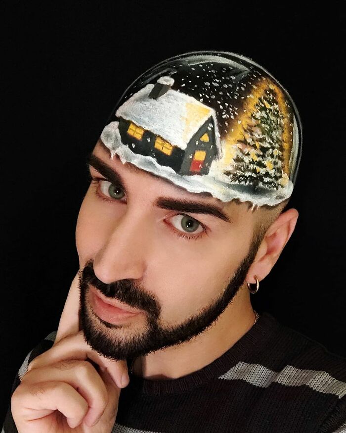 Italian artist uses his head as a canvas with body paint creating a convincing optical illusion of a snowy cabin and tree.