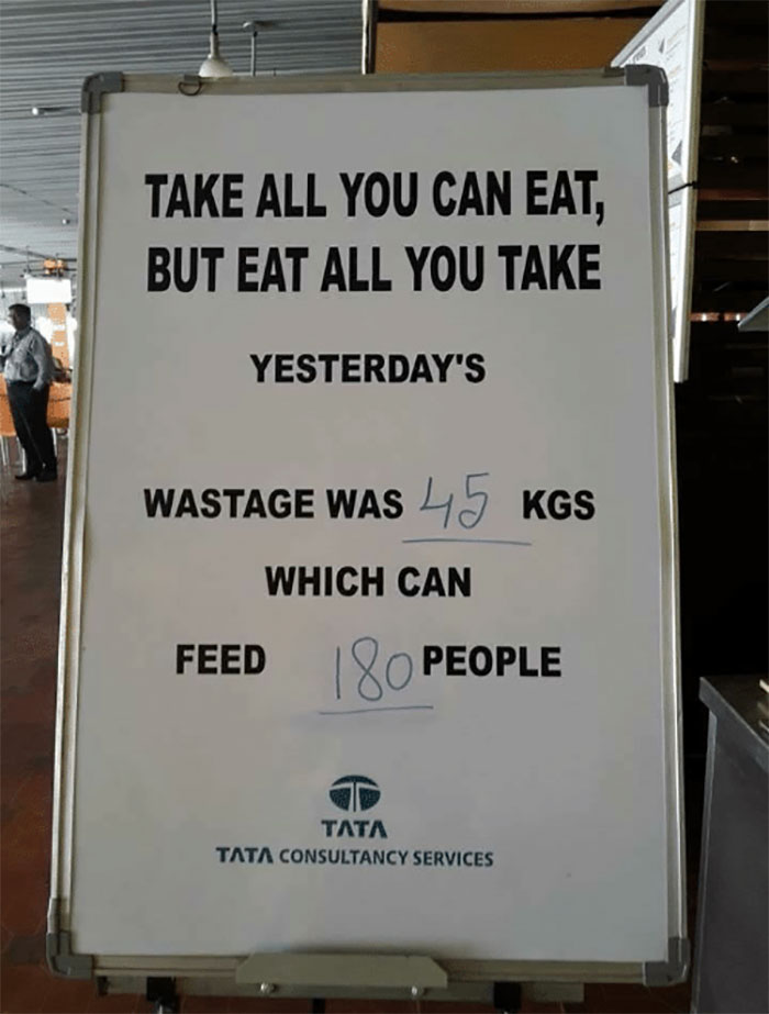 Signboard promoting anti-consumption with a message about food wastage and its impact, displayed in a corporate setting.
