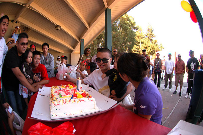 Group of people celebrating with a colorful birthday cake under a pavilion, capturing moments for online group not-so-fun facts discussion