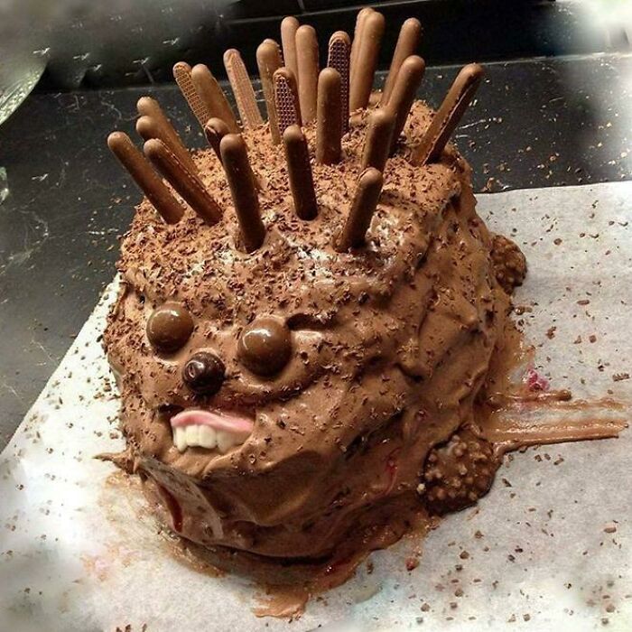 A humorous cake fail shaped like a hedgehog with chocolate sticks.
