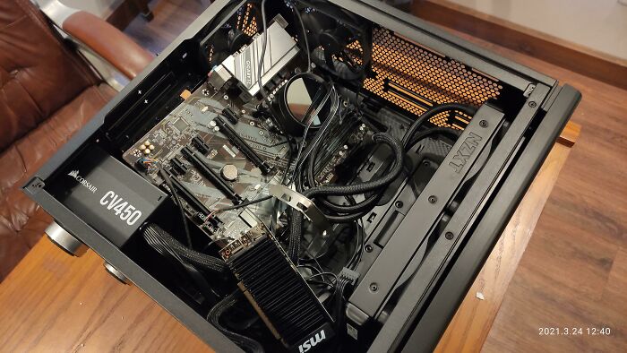 Open computer case with gaming hardware showing an MSI graphics card and Corsair power supply unit inside.