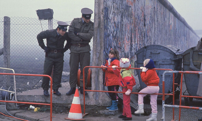 Children interacting with guards at the Berlin Wall, offering a historical perspective.