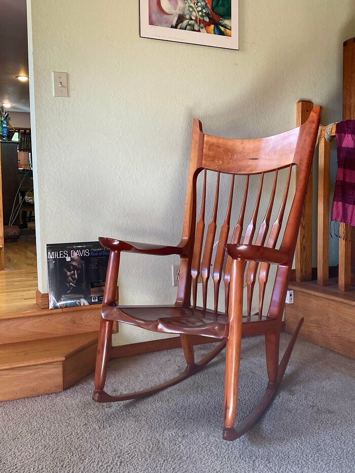 Handcrafted wooden rocking chair with a smooth polished finish displayed in a cozy indoor setting.