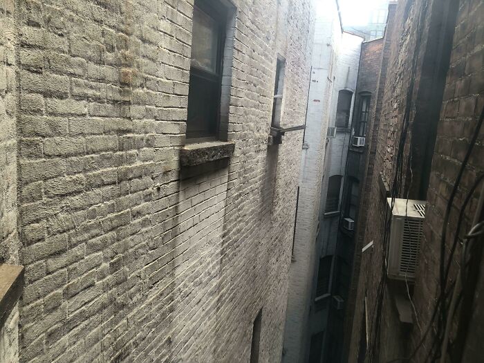 Narrow urban alley with old brick walls and air conditioning units, depicting a real urban hell dystopian scene.