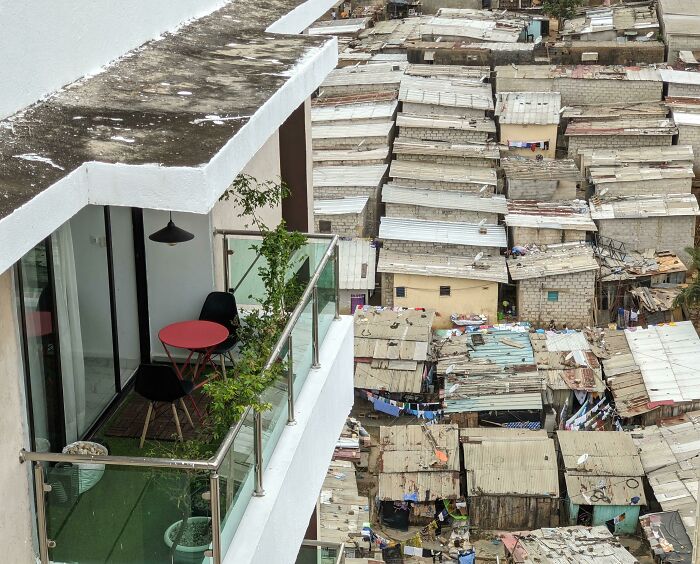 Balcony overlooking dense urban hell with tightly packed makeshift homes in a dystopian cityscape setting.