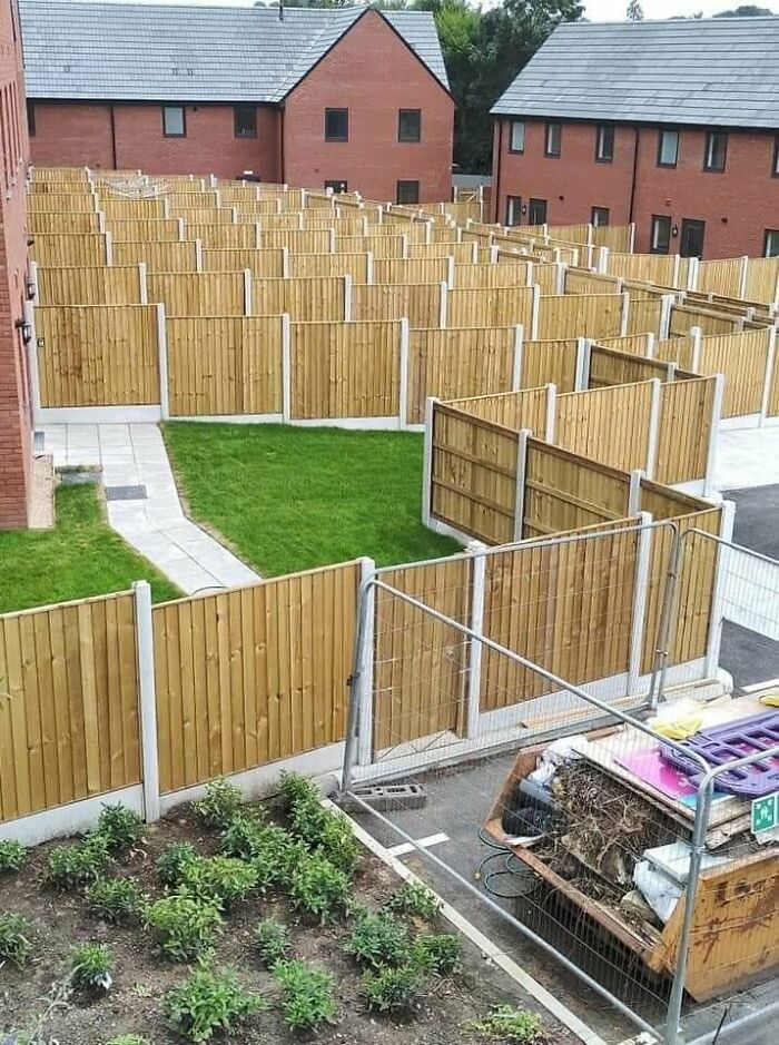 Wooden fences densely packed in a small residential area, creating a confusing maze-like urban hell scene.