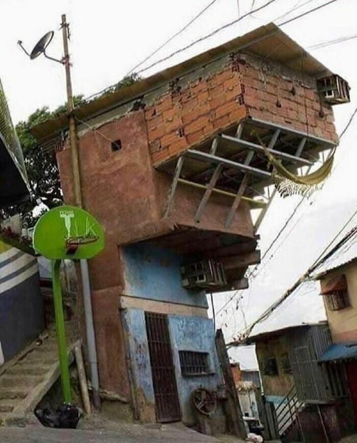 Unusually constructed house leaning on a steep street with a basketball hoop and hammock, showcasing weird Instagram account content.