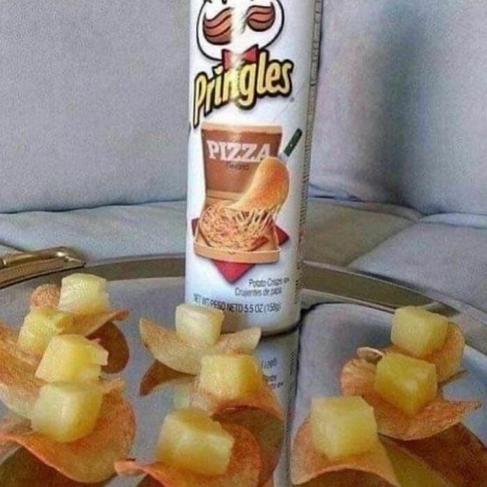 Pringles pizza flavor chips topped with small pineapple cubes on a reflective surface, showcasing a weird food combination.