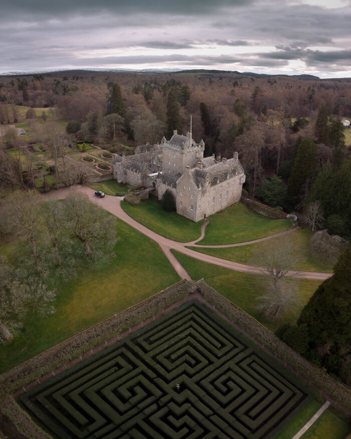 Aerial view of one of the most beautiful castles surrounded by gardens, pathways, and a large hedge maze.